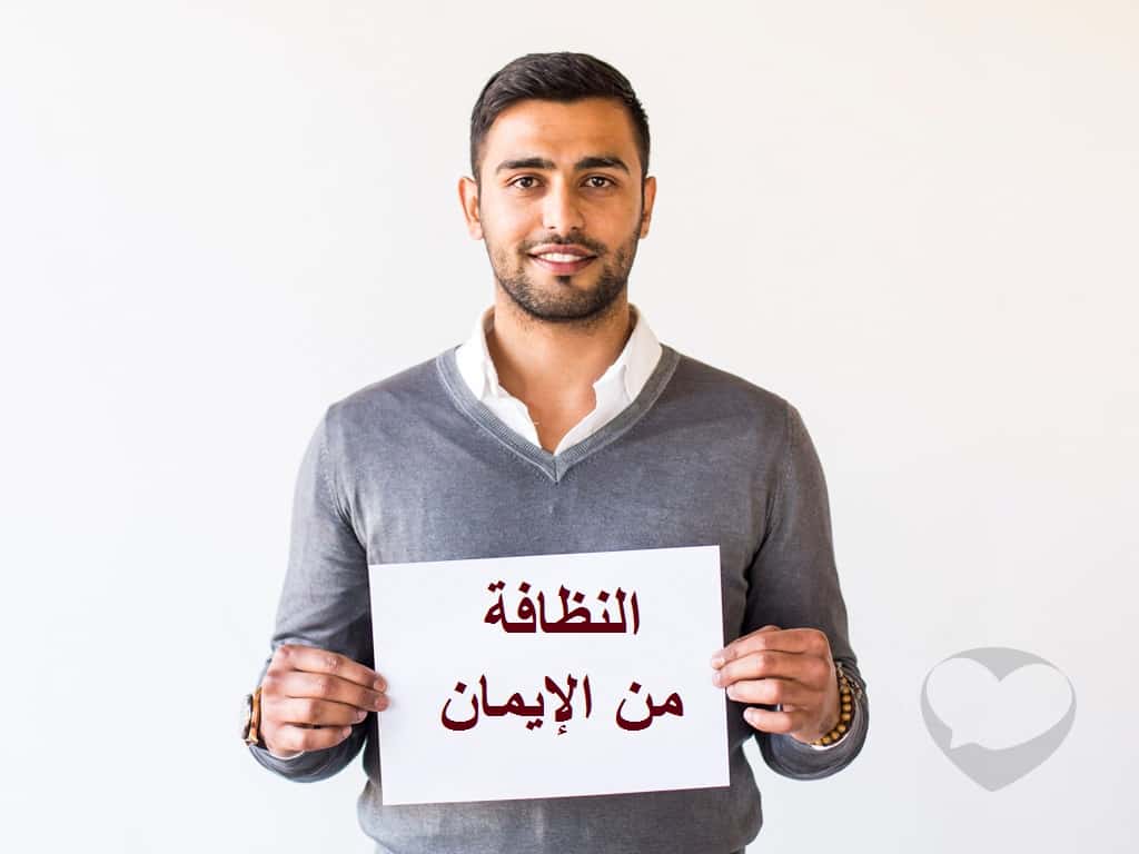 شاب يحمل ورقة مكتوب عليها النظافة من الإيمان