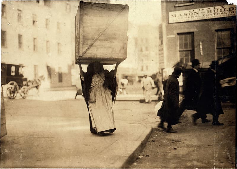 صورة قديمة لامرأة تحمل صندوق كبير فوق رأسها