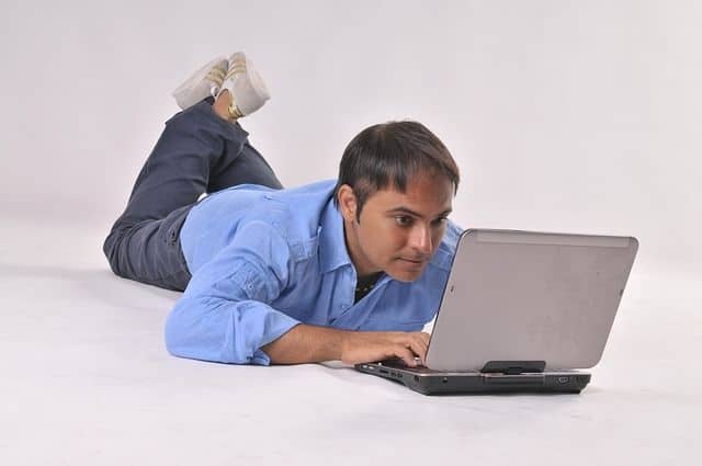 شاب مستلقي ويجلس أمام كمبيوتر المحمول