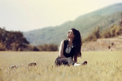 امرأة تجلس في الحقول مستمتعة بالطبيعة