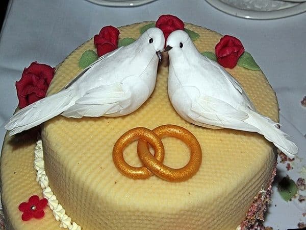 كعكة زفاف مزينة بالحمام الابيض وخاتم الزواج